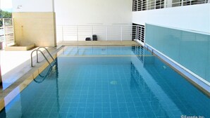 A swimming pool with a tiled floor, a metal ladder, and a white railing. - Primavera Residences (Cagayan de Oro)