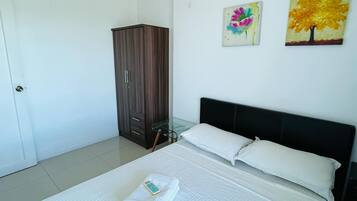 A hotel room with a bed, a wardrobe, and two paintings on the wall.