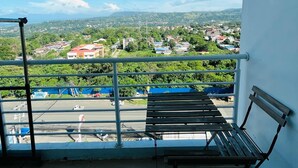 A balcony with a view of a town, a bench, and a railing. - Primavera Residences (Cagayan de Oro)