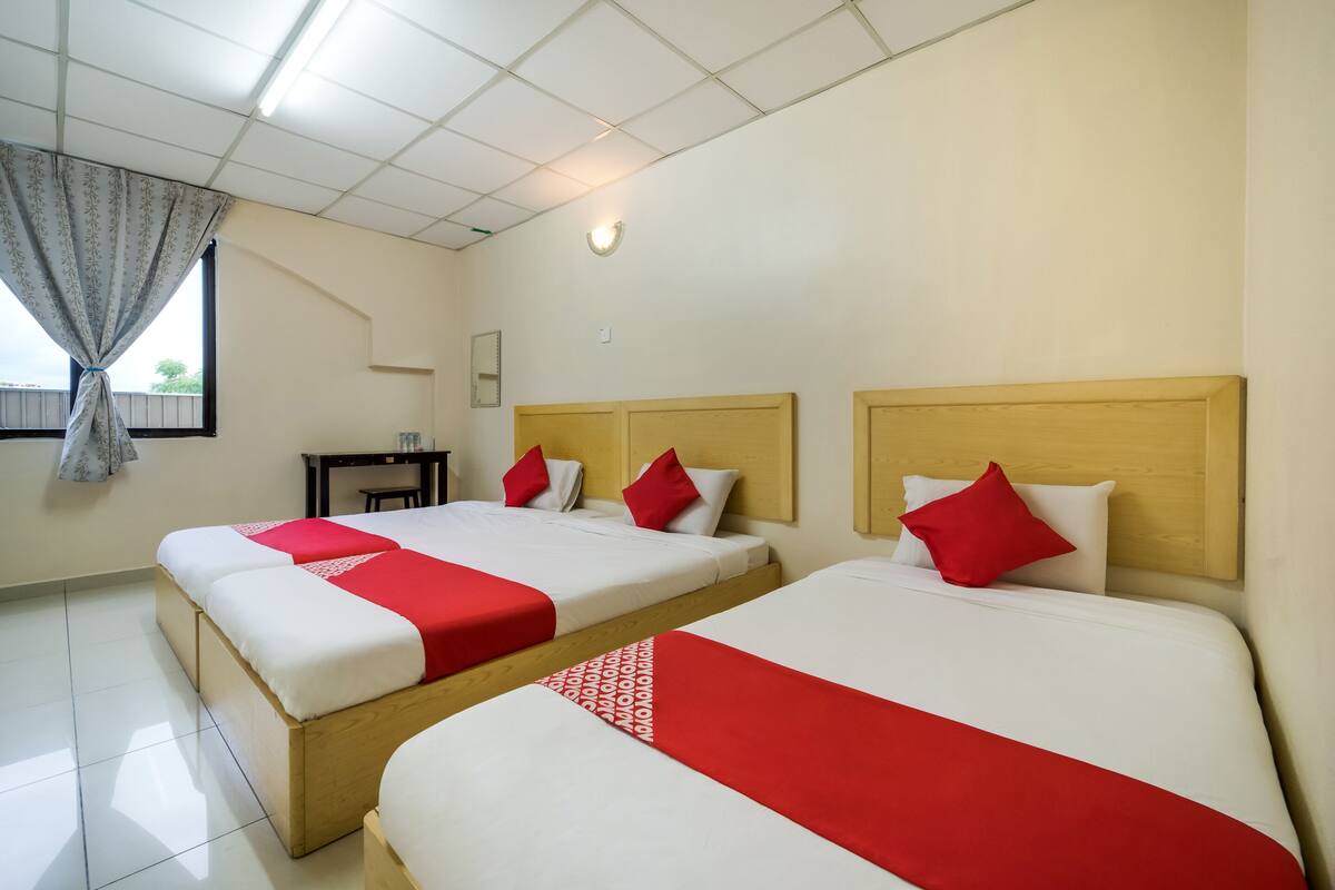 Hotellihuone, jossa on kaksi sänkyä, ja jokaisessa sängyssä on puinen pääty ja punavalkoiset vuodevaatteet.