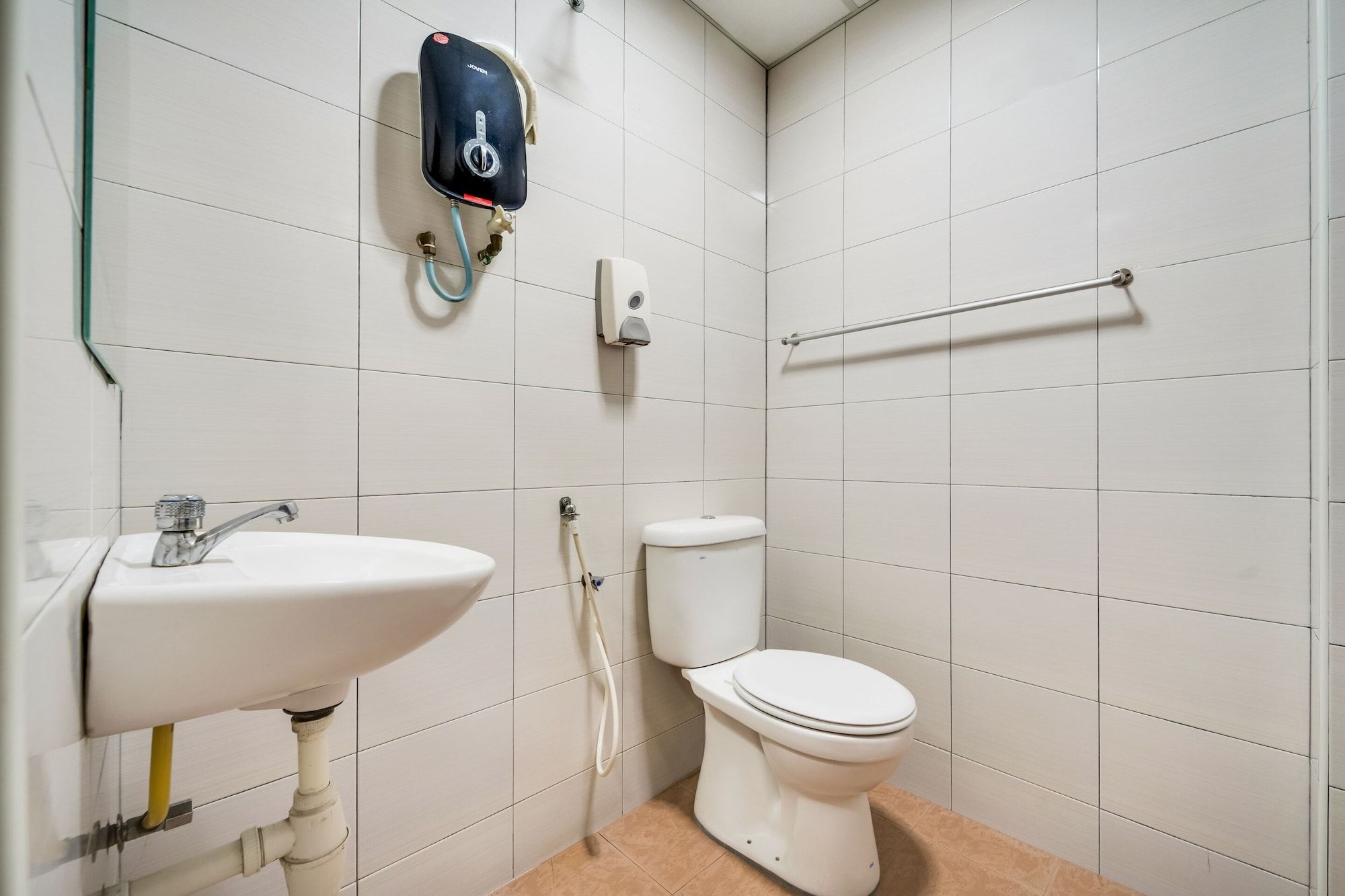 A bathroom with a white sink, toilet, and a handheld showerhead mounted on the wall.