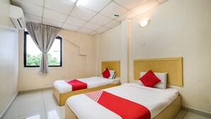 A hotel room with two beds, a window with a curtain, and an air conditioning unit. - River Inn Hotel (Butterworth)