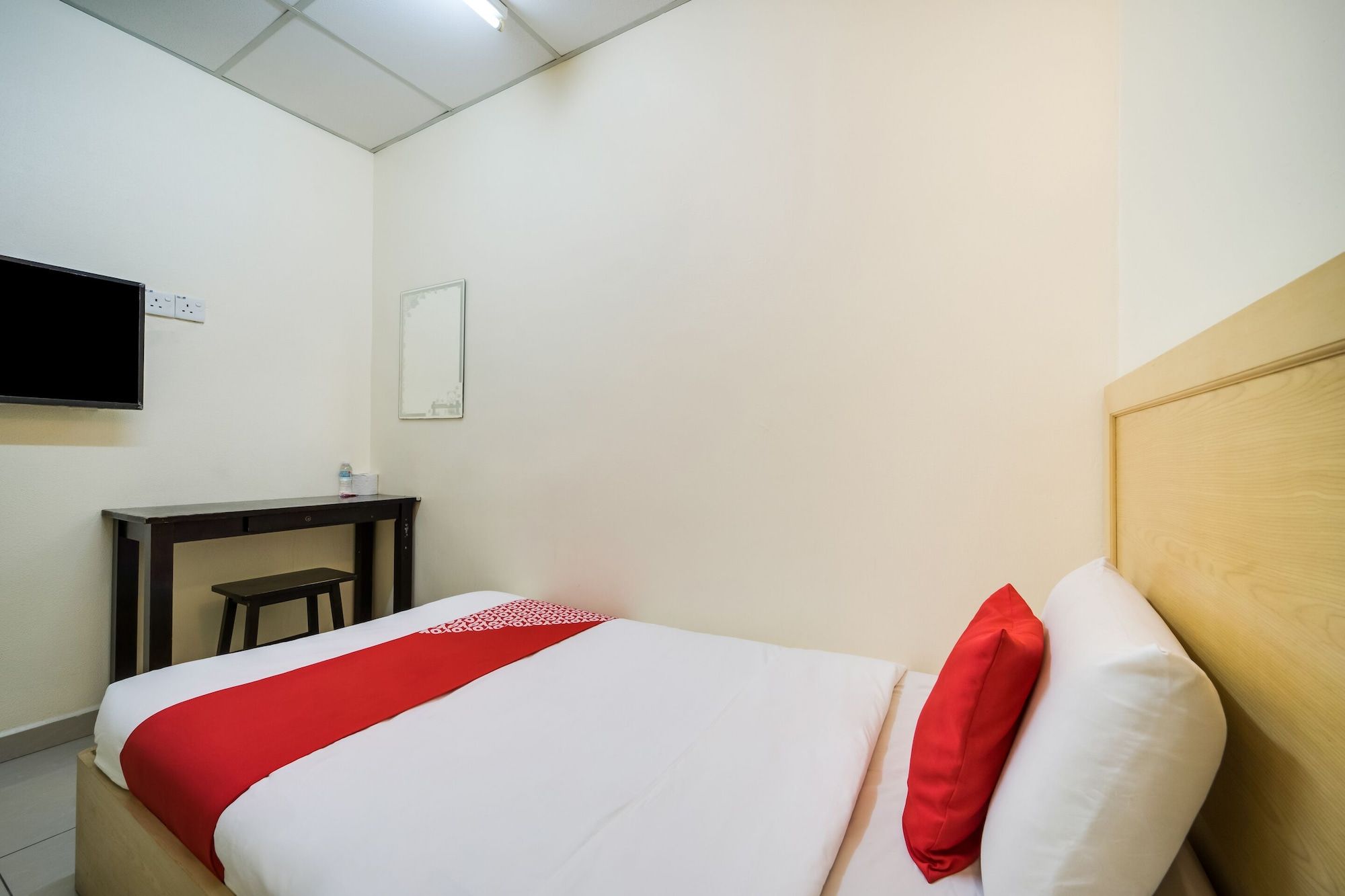Una camera d'albergo con un letto, una scrivania, una sedia, una televisione e uno specchio.