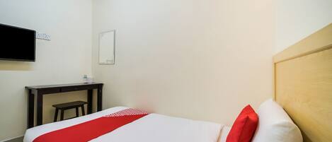 Una camera d'albergo con un letto, una scrivania, una sedia, una televisione e uno specchio.
