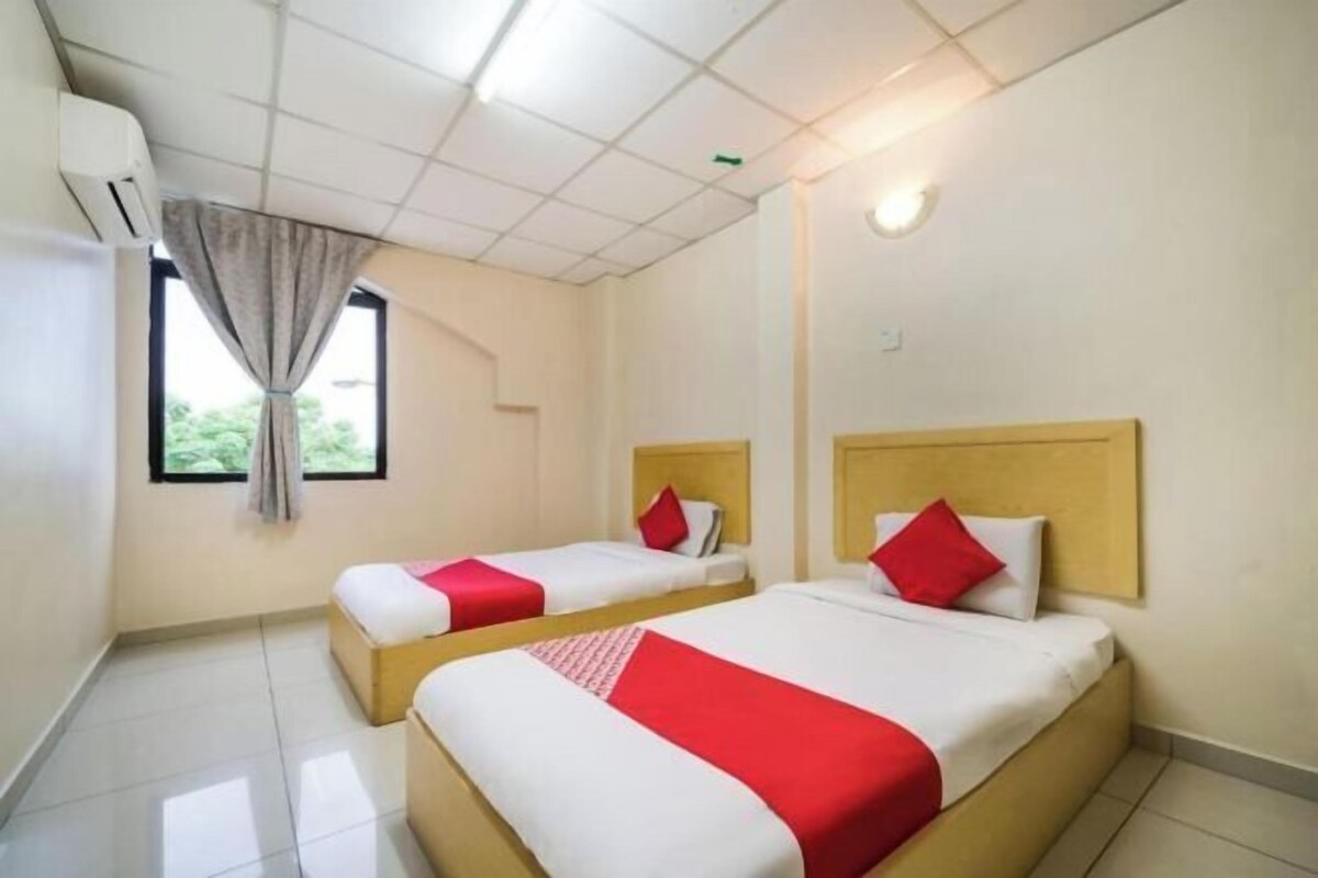 A hotel room with two beds, a window with a curtain, and a ceiling air conditioner.