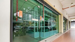 A modern building with large glass windows, a sign reading "River Inn," and a reflection of parked cars outside. - River Inn Hotel (Butterworth)