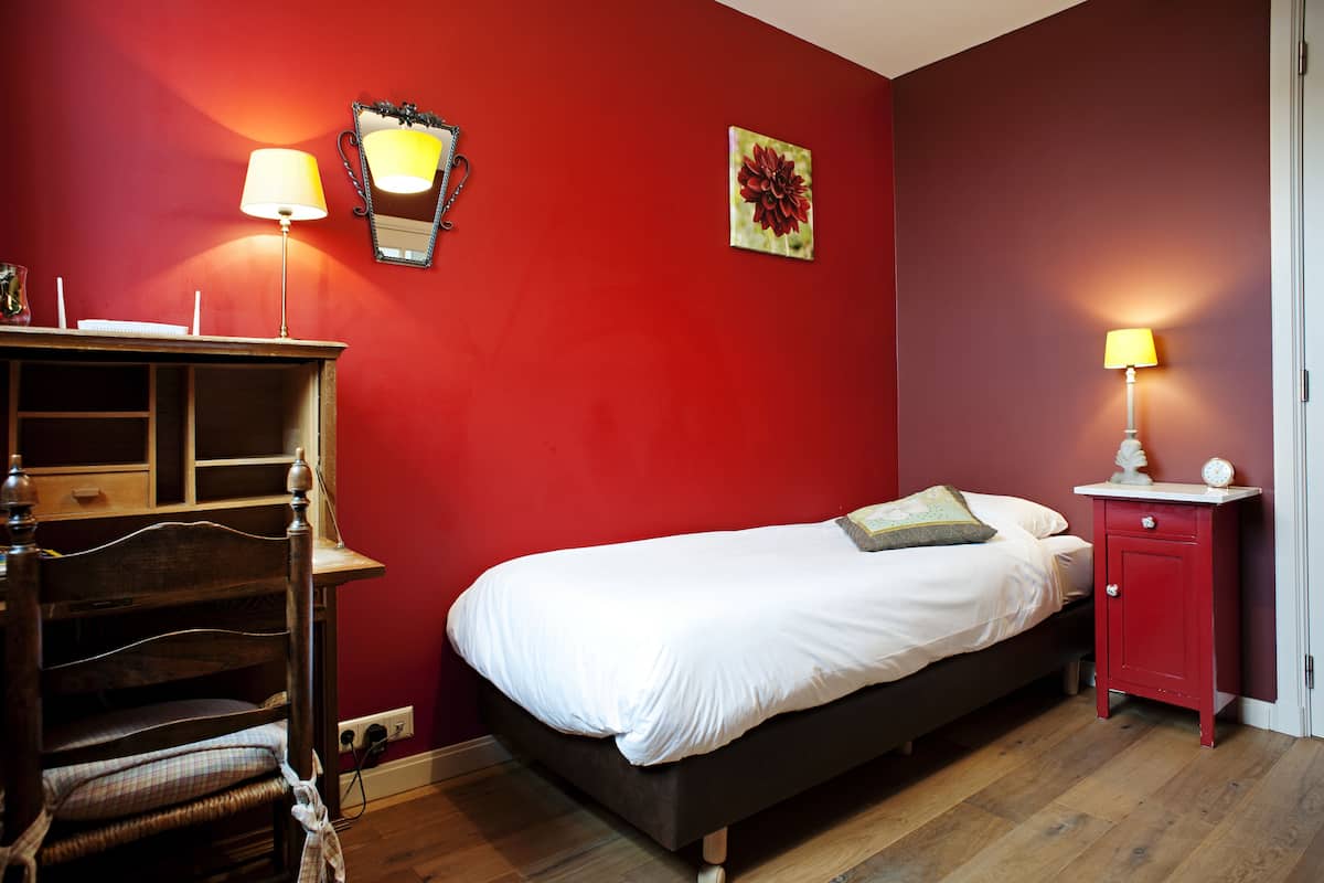 A bedroom with a bed, a dresser, a nightstand, and a lamp.