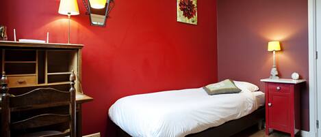 A bedroom with a bed, a dresser, a nightstand, and a lamp.