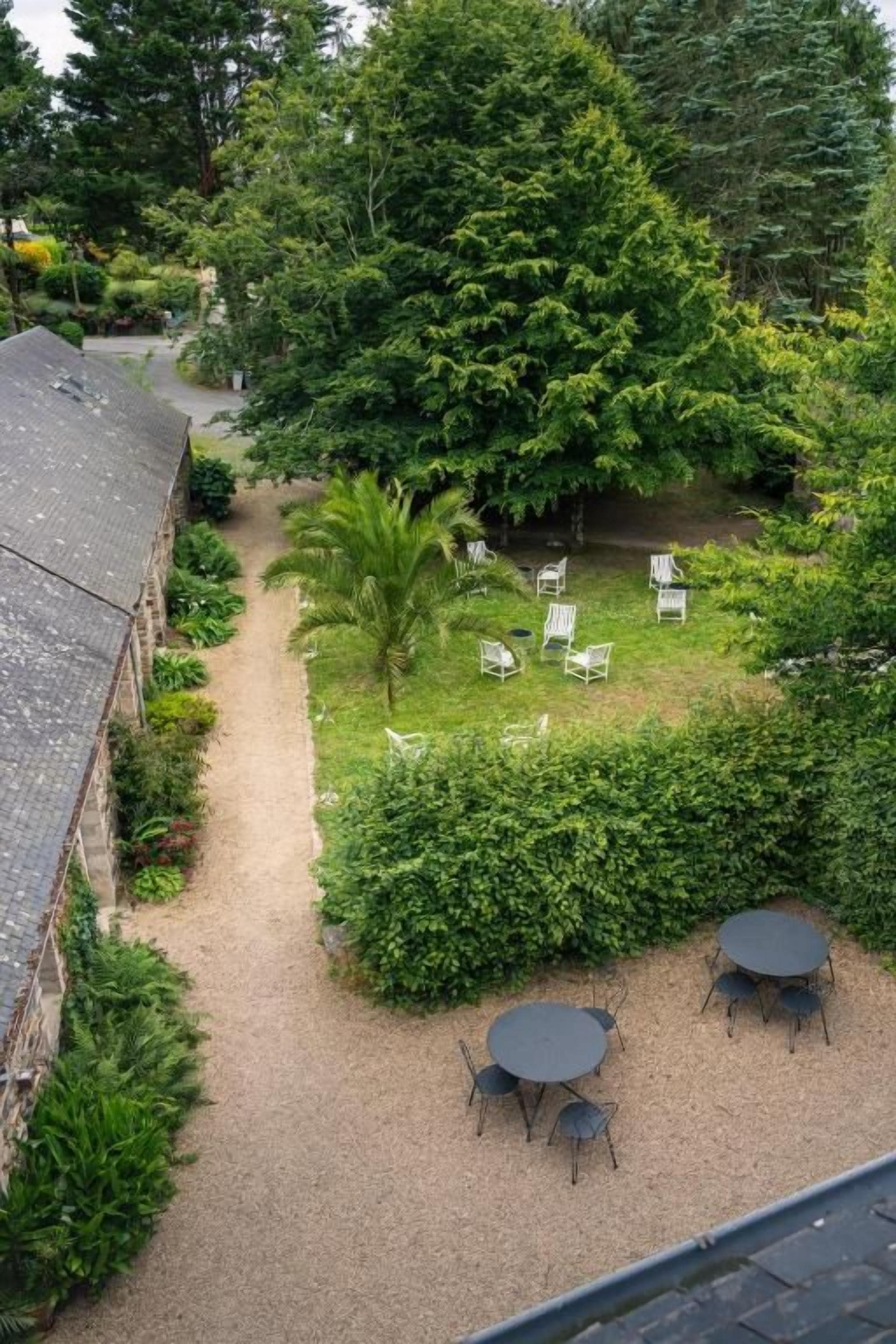 A courtyard with a gravel path, a palm tree, and outdoor seating.