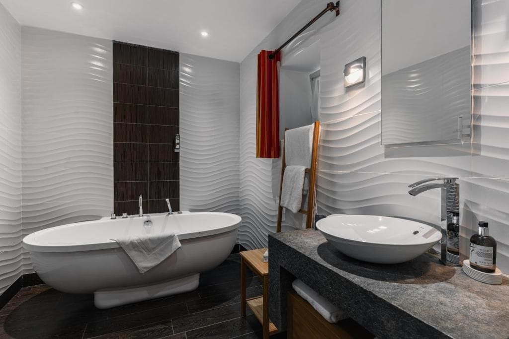 Un bany modern amb banyera independent, un lavabo i un mirall.