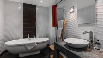 Un bany modern amb banyera independent, un lavabo i un mirall.