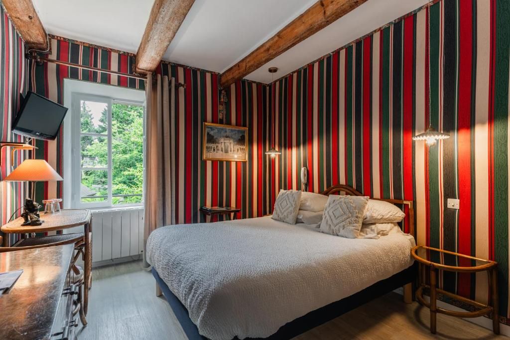 Een kamer met een bed, een bureau, een stoel, een televisie en een raam met uitzicht op groen.