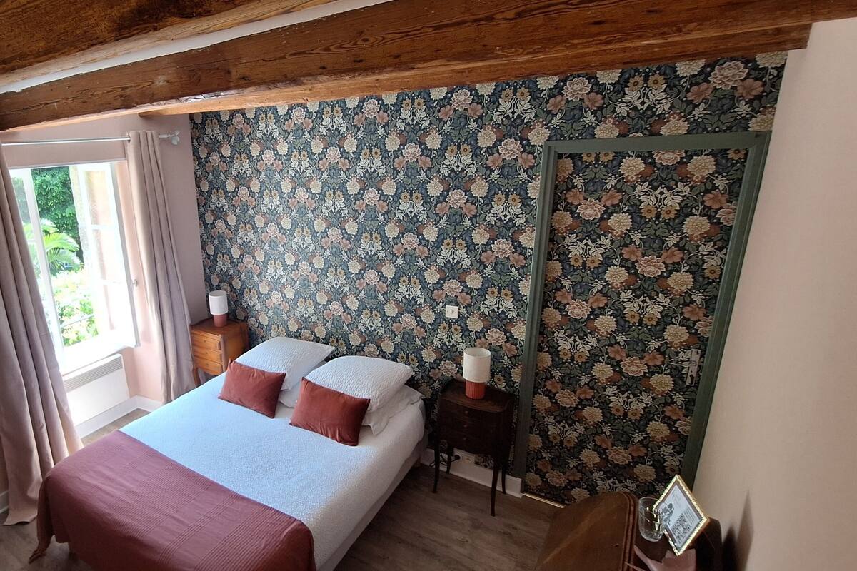 Un dormitorio con cama, cómoda, espejo y ventana con cortinas.