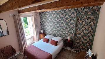 A bedroom with a bed, a dresser, a mirror, and a window with curtains.