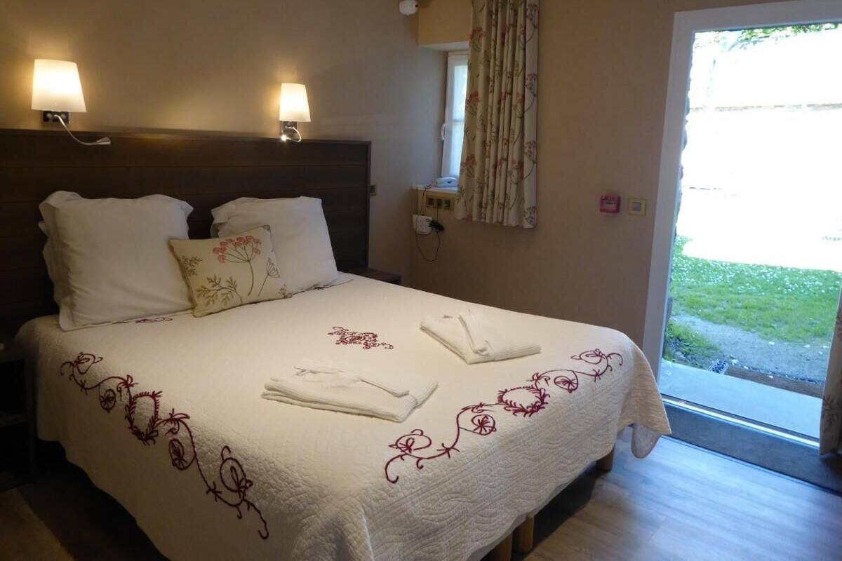 Habitación de hotel con cama, dos lámparas de pared, una ventana con cortinas y vistas al exterior.