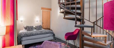 Un dormitorio con cama, una silla, una escalera de madera y una puerta.
