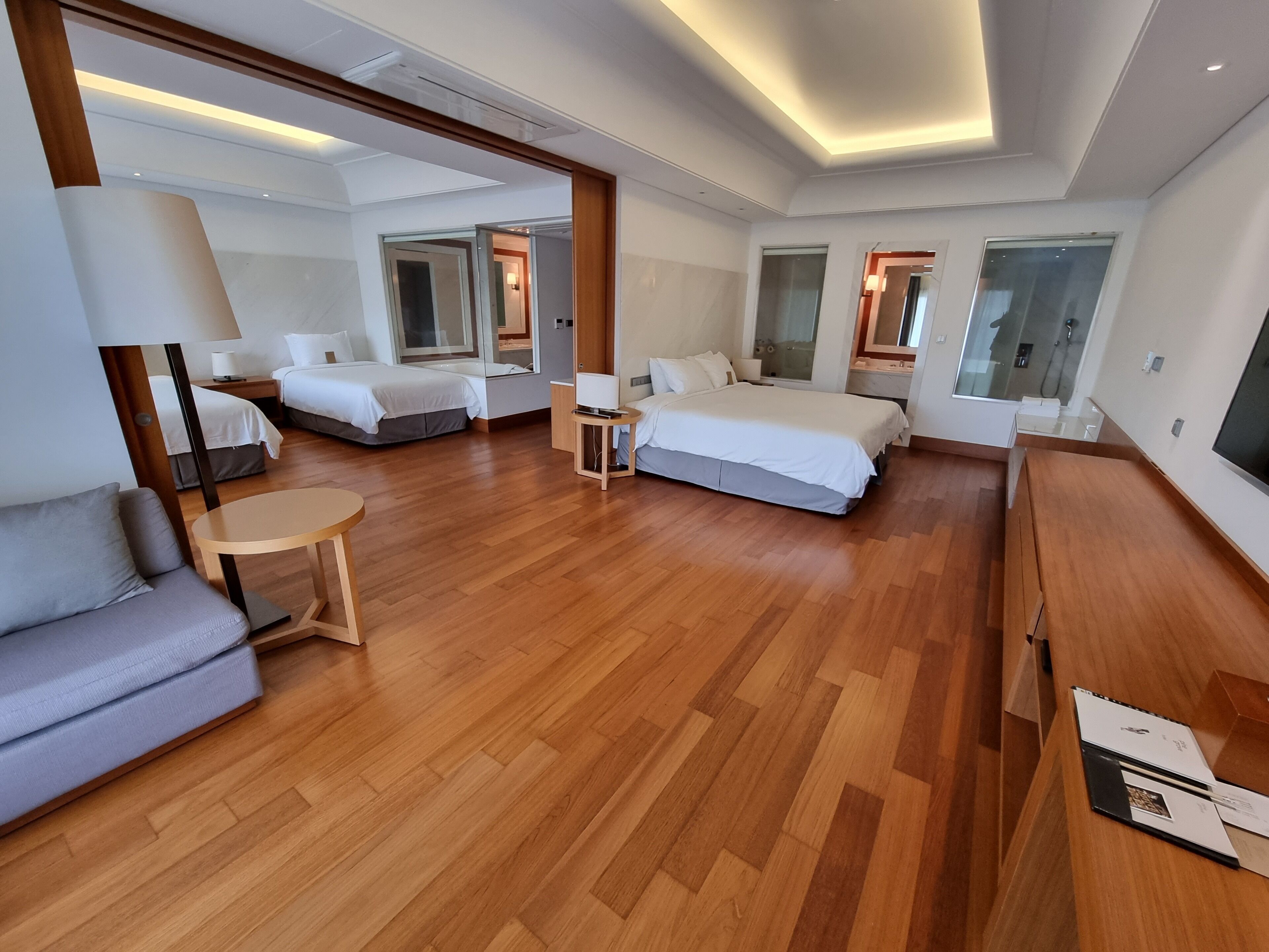 Una habitación de hotel moderna con una cama grande, un sofá, una mesita y un televisor.