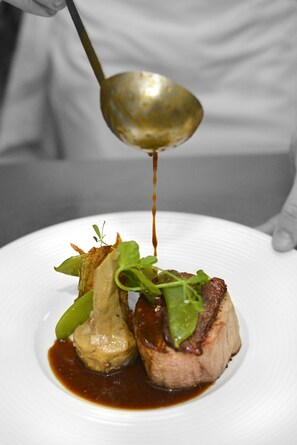 A chef pouring sauce over a dish on a white plate. - Hotel La Villa des Bordes (Clery-Saint-Andre)