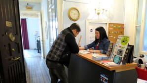A reception desk with a clock, a sign for low-cost bike rentals, and a wall-mounted bike rack. - Hostal Balmes Centro (Barcelona)