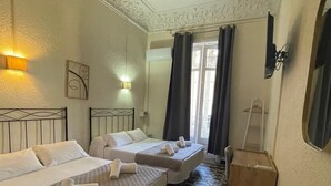 A hotel room with two beds, a tiled floor, a wooden nightstand, and a large mirror. - Hostal Balmes Centro (Barcelona)