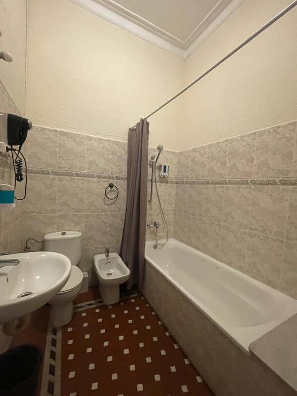 A bathroom with a sink, bidet, toilet, and bathtub.