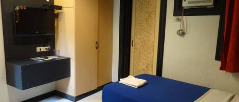 A hotel room with two beds, a minibar, a mirror, a wardrobe, and a wall-mounted air conditioning unit.