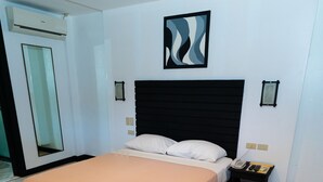 A modern bedroom with a bed, bedside table, and a wall-mounted artwork. - Davao Royal Suites and Residences (Davao)