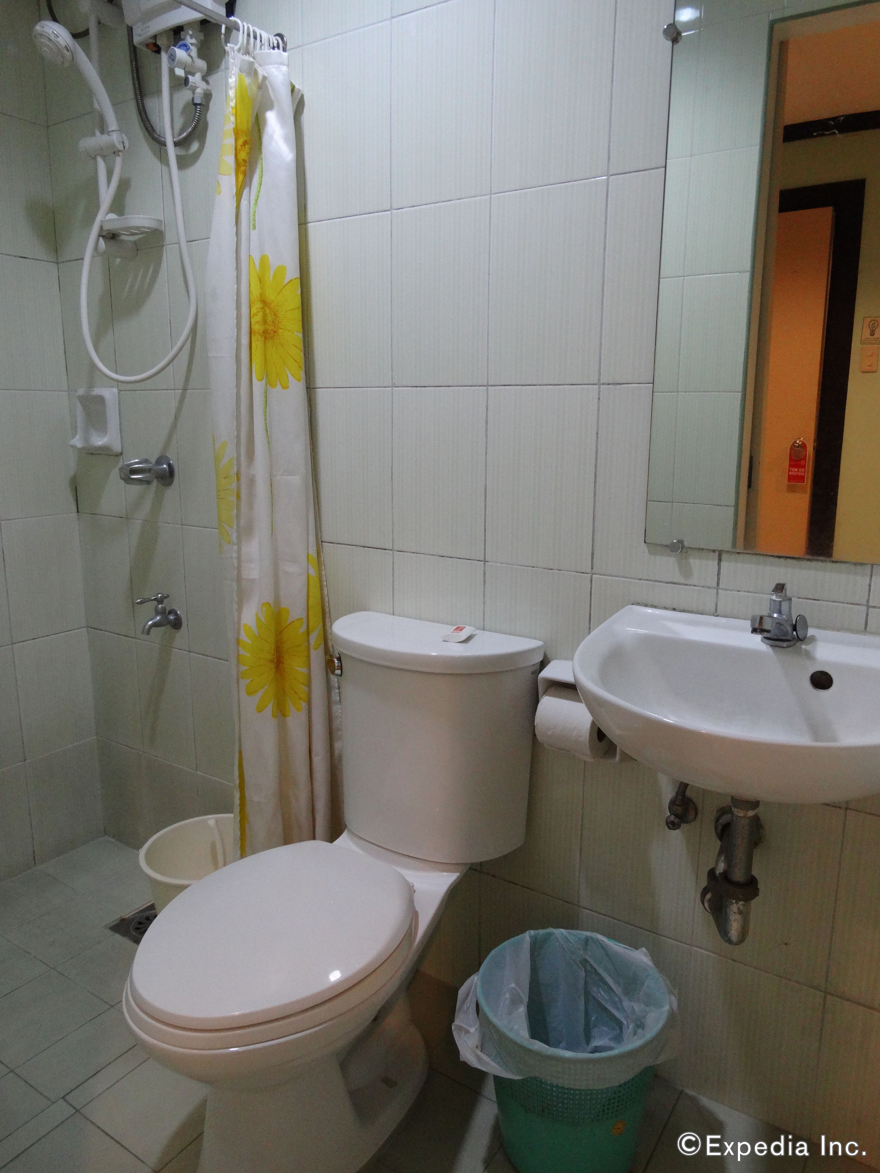 Une salle de bain équipée de toilettes, d’un lavabo, d’une douche et d’une poubelle.
