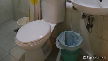 Une salle de bain équipée de toilettes, d’un lavabo, d’une douche et d’une poubelle.