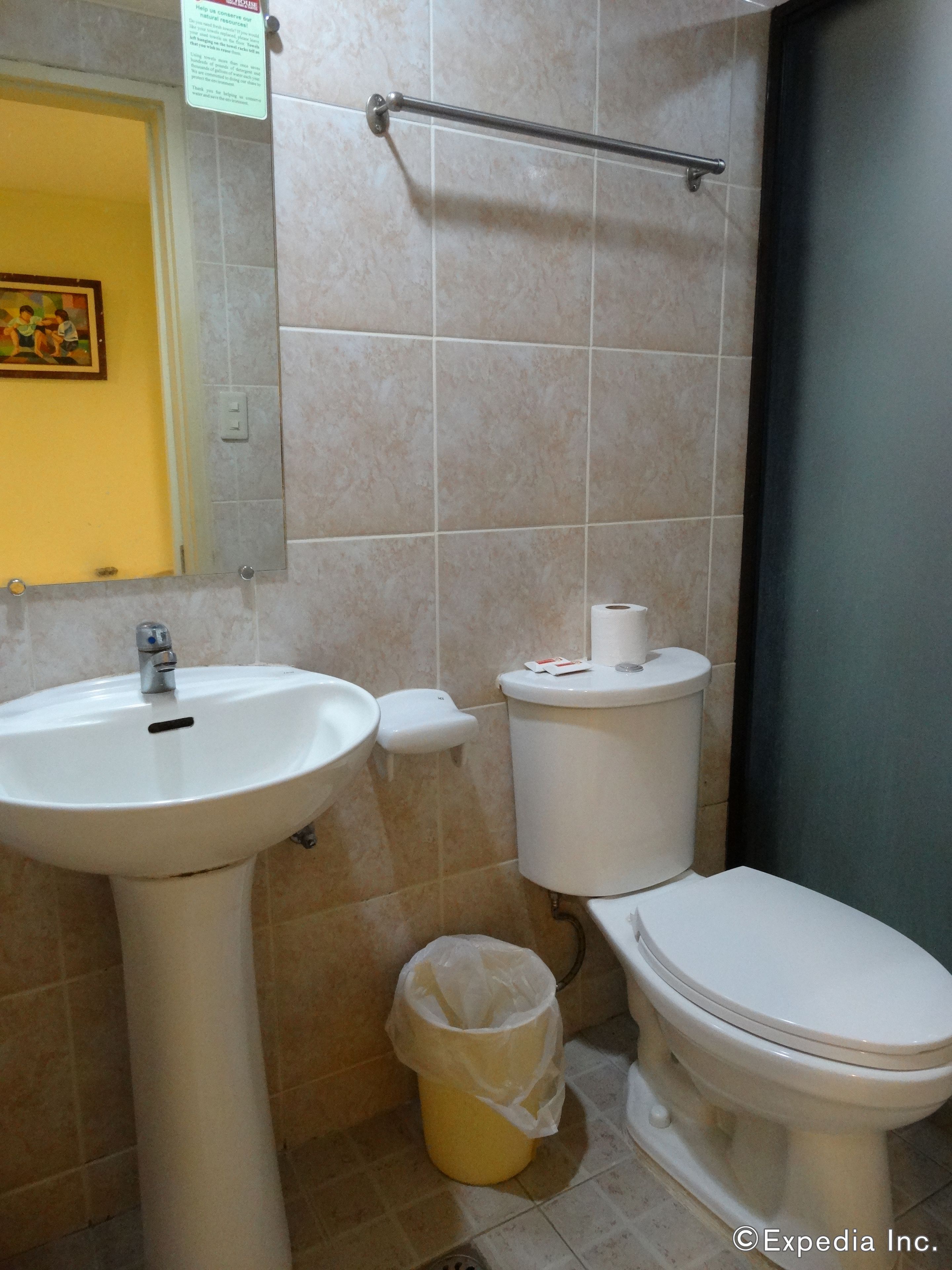 A bathroom with a sink, toilet, and a trash can.