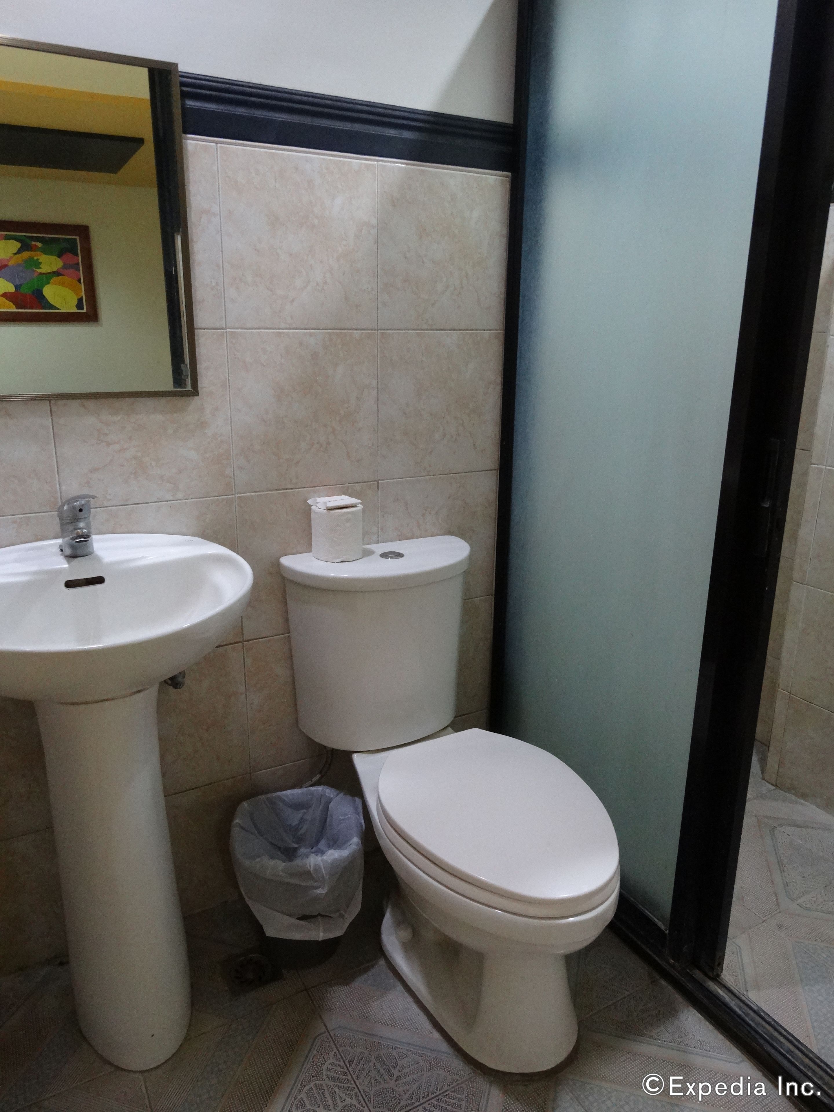 A bathroom with a sink, toilet, and a trash bin.