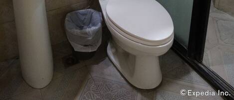 Un baño con lavamanos, inodoro y un cubo de basura.