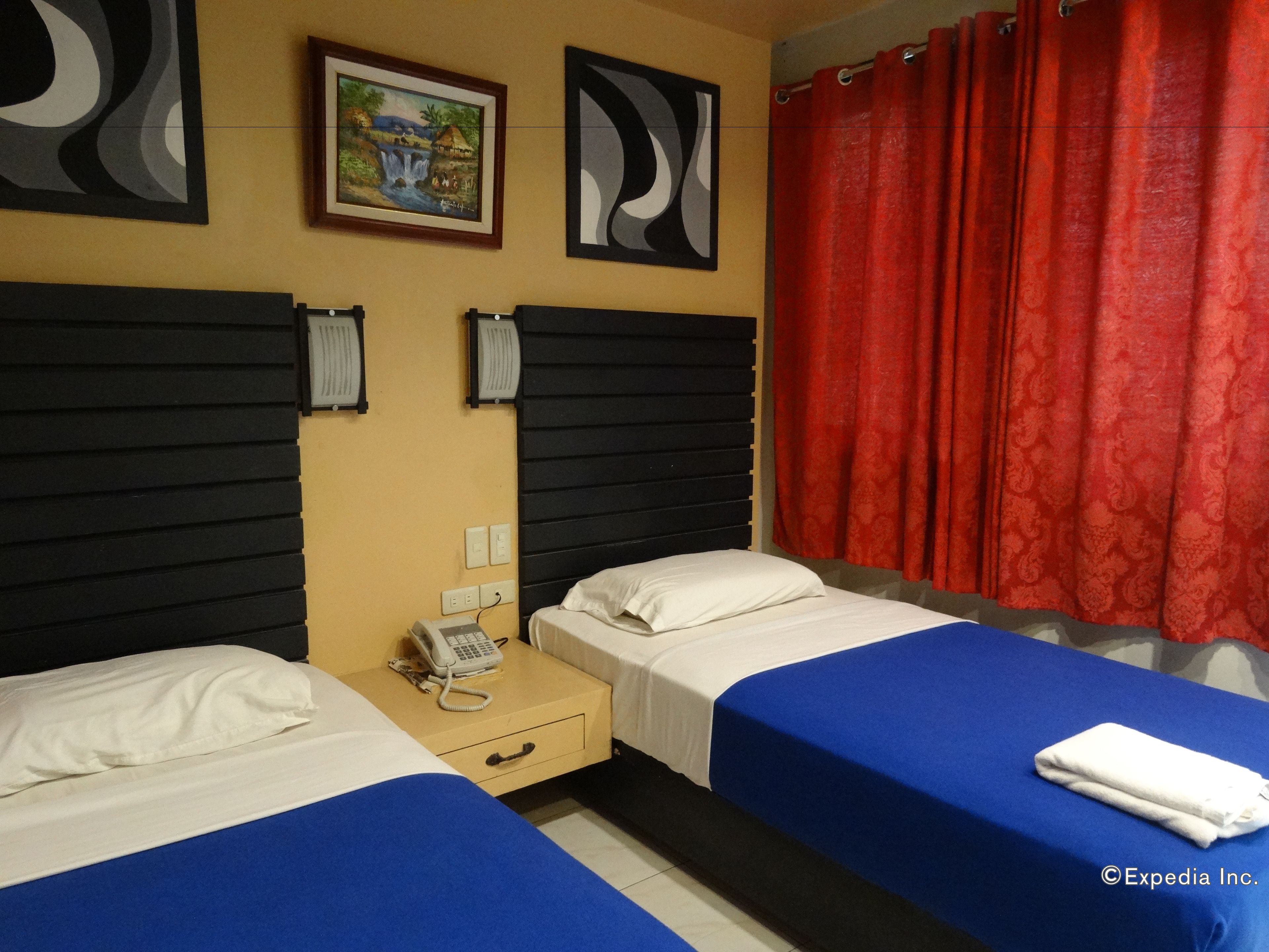 A hotel room with two beds, a nightstand with a phone, and a painting on the wall.