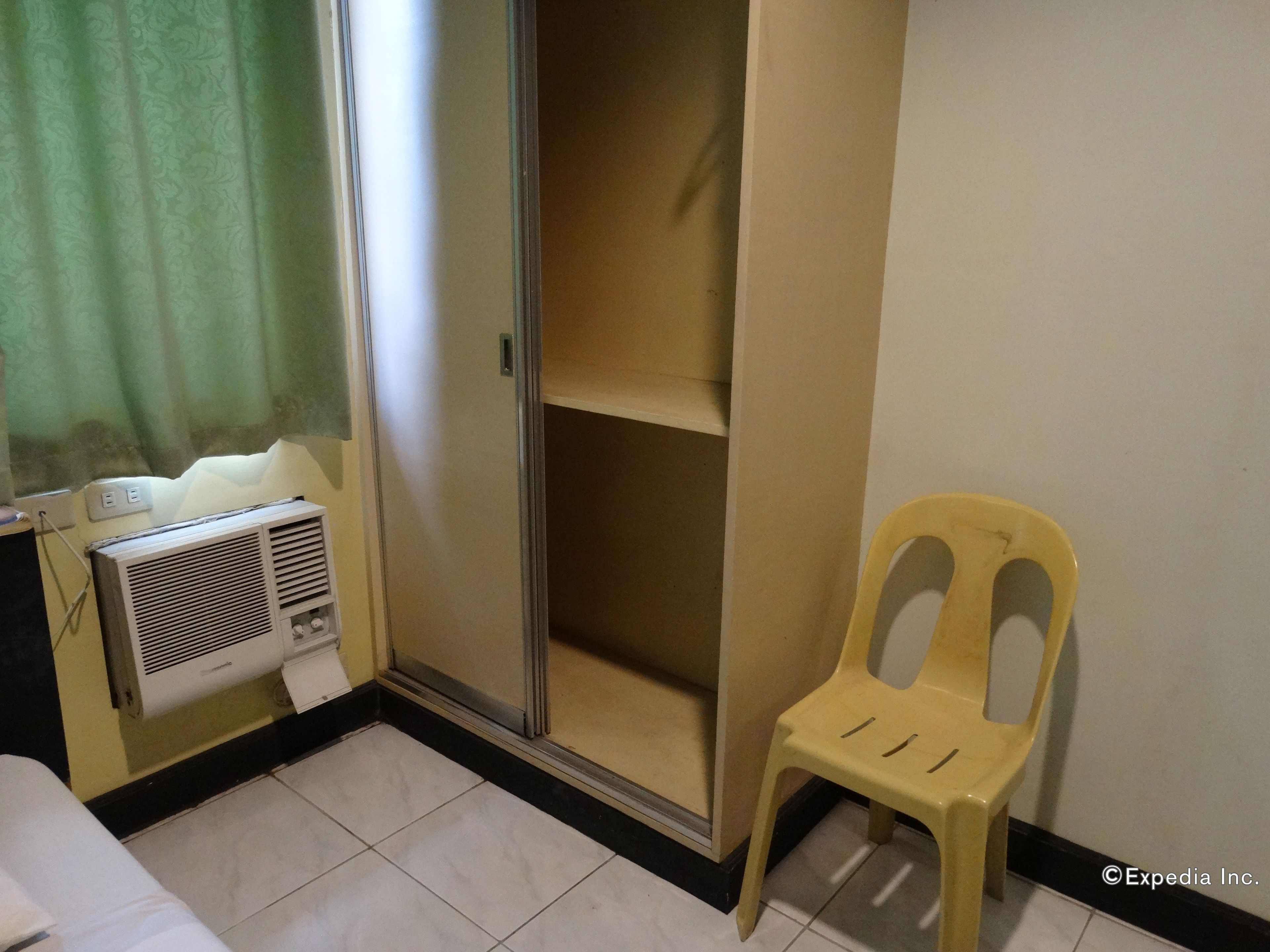 A room with a sliding door closet, a yellow plastic chair, and a wall-mounted air conditioner.
