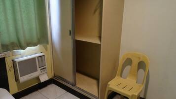A room with a sliding door closet, a yellow plastic chair, and a wall-mounted air conditioner.