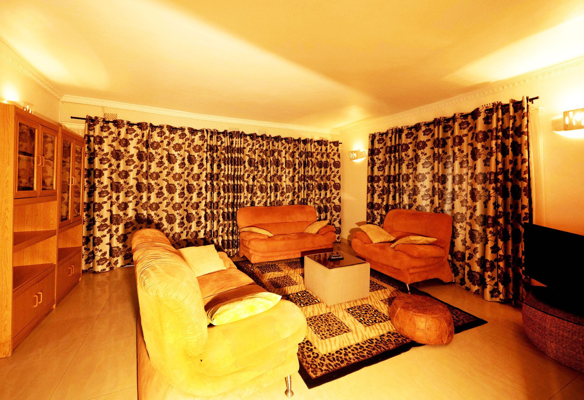 Una sala de estar con un sofá, dos sillones, una mesa de centro y un televisor.