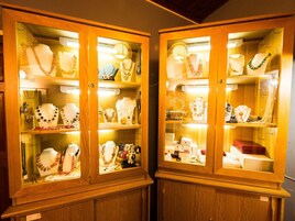 Two wooden display cabinets with glass doors, each containing various jewelry items.
