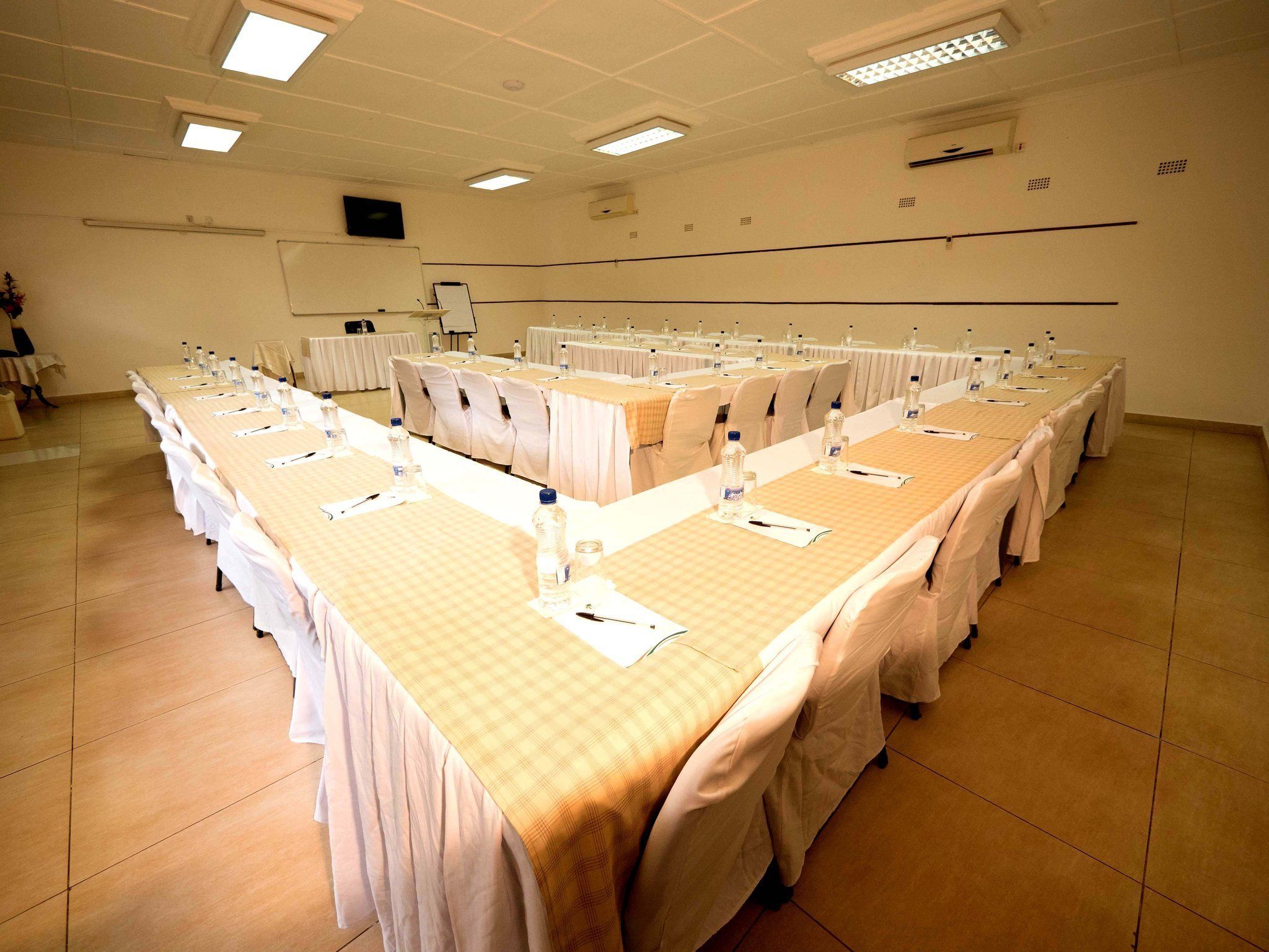 A conference room with long tables, chairs, and a whiteboard.