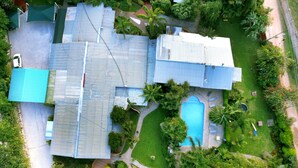 An aerial view of a residential area with multiple houses, a swimming pool, and lush greenery. - Palmwood Lodge (Lusaka)