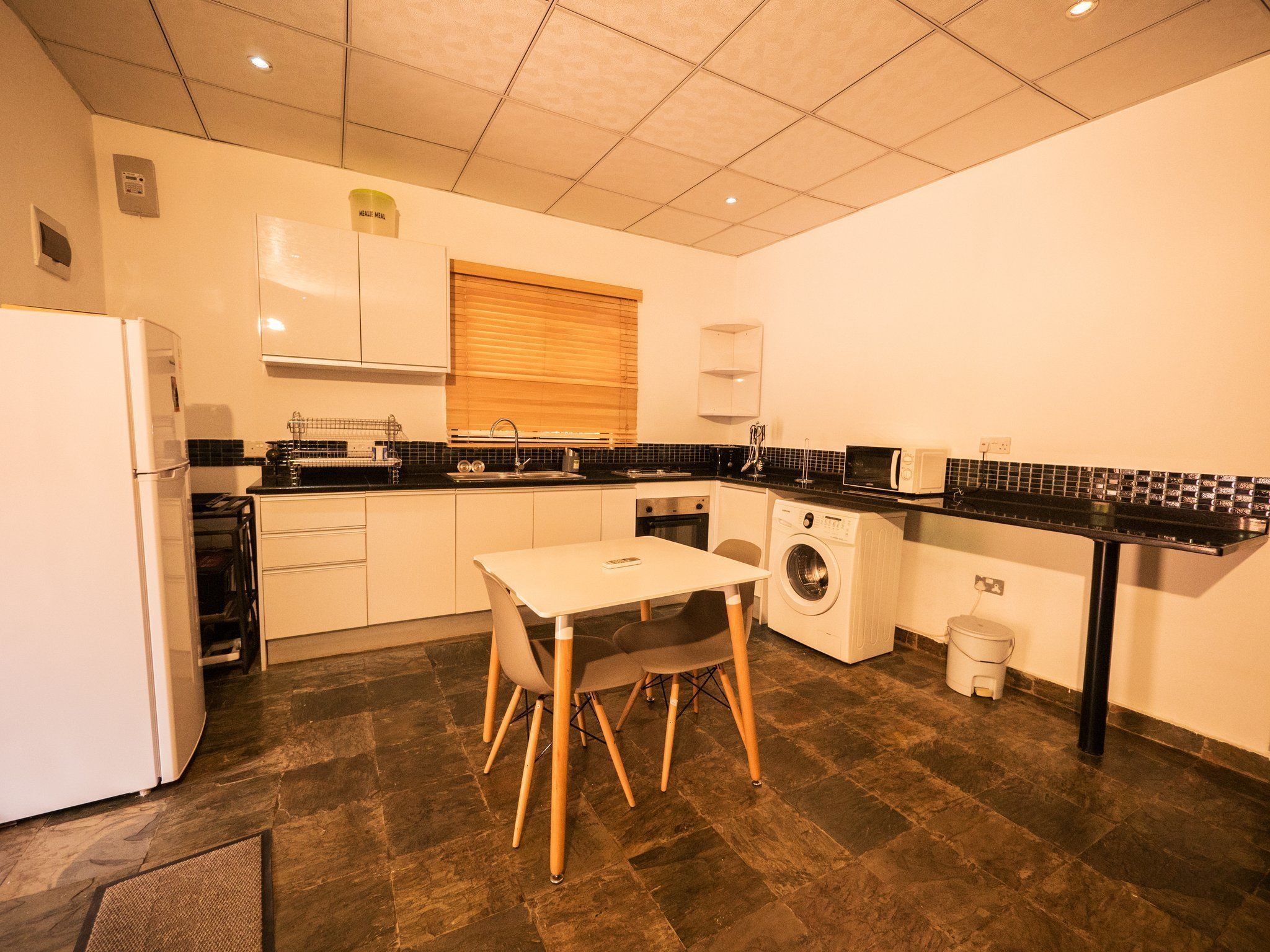 A compact kitchen with a refrigerator, sink, microwave, and a washing machine.