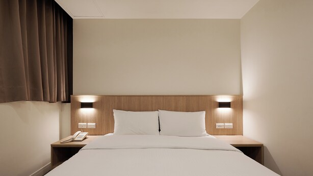 A hotel room with a large bed, two bedside tables, a wooden headboard, and two wall-mounted lights. - Nei Jiang Hotel (Taipei)