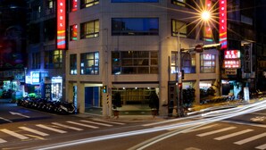 A multi-story hotel with a prominent red vertical sign on the facade, multiple windows, and a street view with a crosswalk and parked motorcycles. - Nei Jiang Hotel (Taipei)