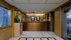 A reception area with a marble floor, wooden paneling, framed certificates on the wall, and a reception desk. - Nei Jiang Hotel (Taipei)