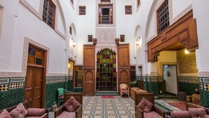 A traditional Moroccan interior with a central archway, wooden furniture, and patterned tile flooring.
