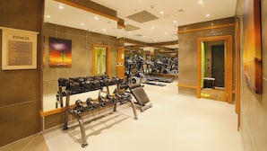 Een sportschool met trainingsapparatuur, spiegels en een fitnessbord.