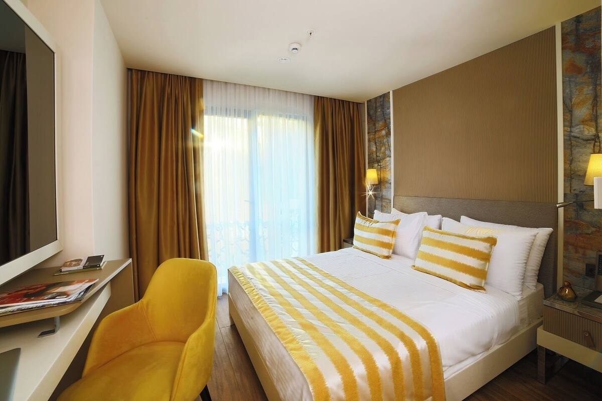 A hotel room with a bed, a desk, a chair, and a TV.