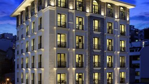 Een hotel met meerdere verdiepingen, een opvallende ingang en een terras.