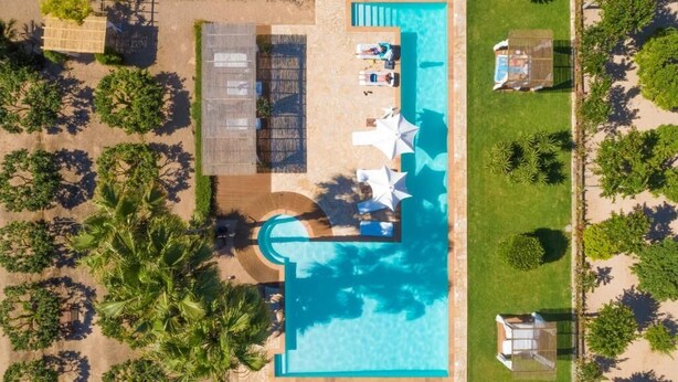 An aerial view of a resort with a swimming pool, sun loungers, and palm trees. - Can Arabi Adults Only (Santa Eulalia del Rio)