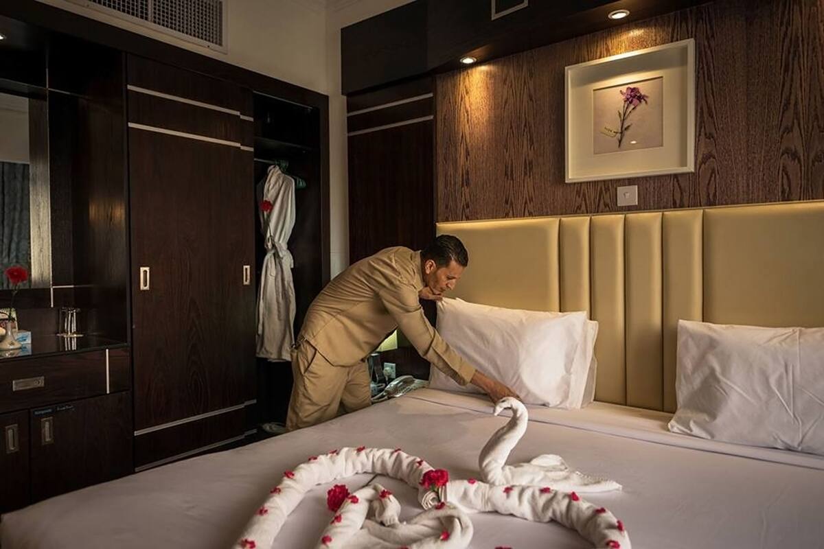 Une chambre d’hôtel avec un lit, un peignoir accroché à la porte et un tableau encadré au mur.