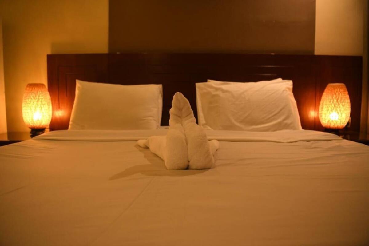 Ein Hotelzimmer mit einem Bett, zwei Kissen und zwei Nachttischlampen.